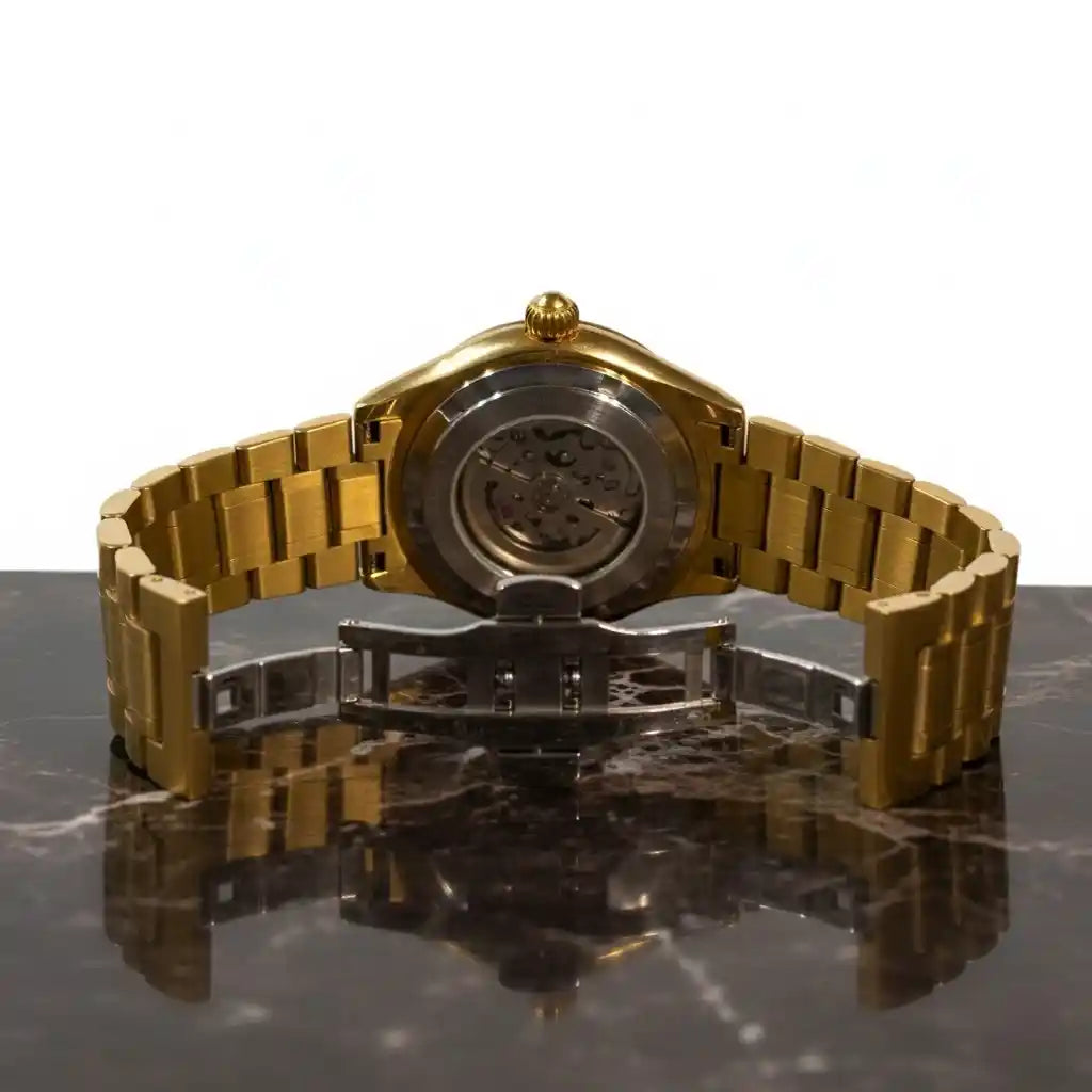 Parte trasera del reloj MVL Double skull dorado con caja abierta y cierre desplegable sobre mármol