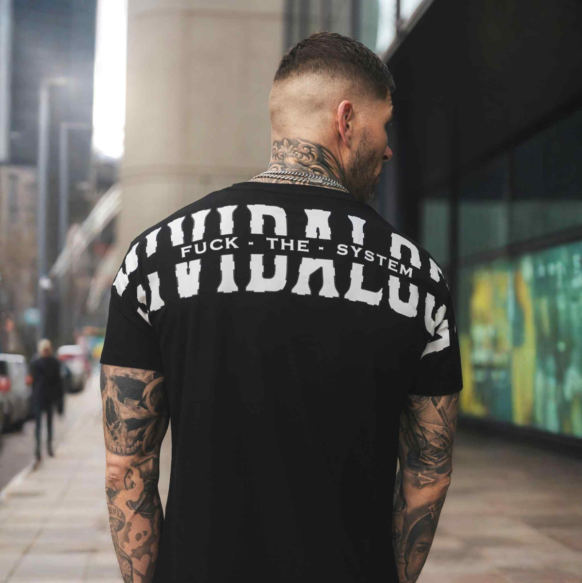 Espalda de la camiseta FTS negra con estampado blanco Mi Vida Loca, llevada por modelo en la calle