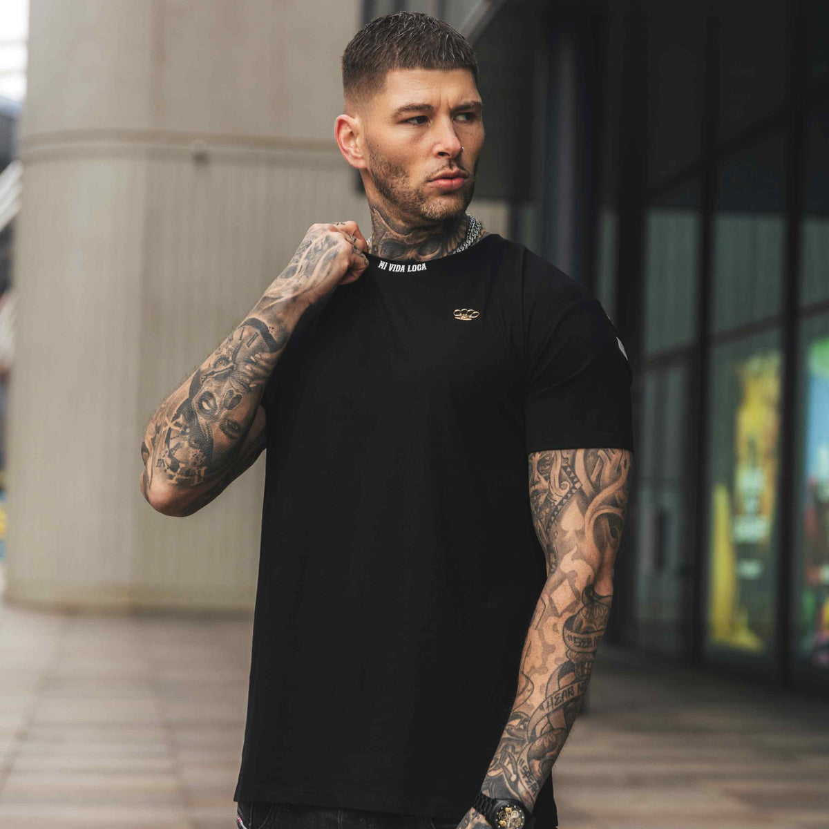 Modelo lleva la camiseta MVL FTS negra, delantera con pequeño logo, en una calle de la ciudad
