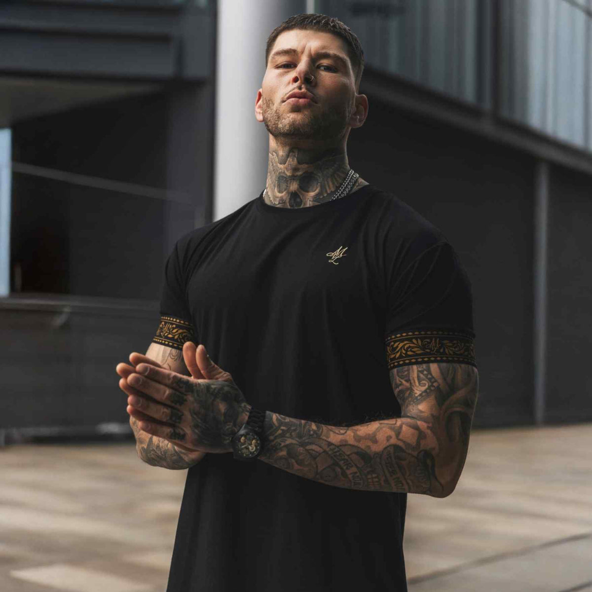 Model im schwarzen MVL Helix T-Shirt mit goldenen Ärmelbändern in der Stadt