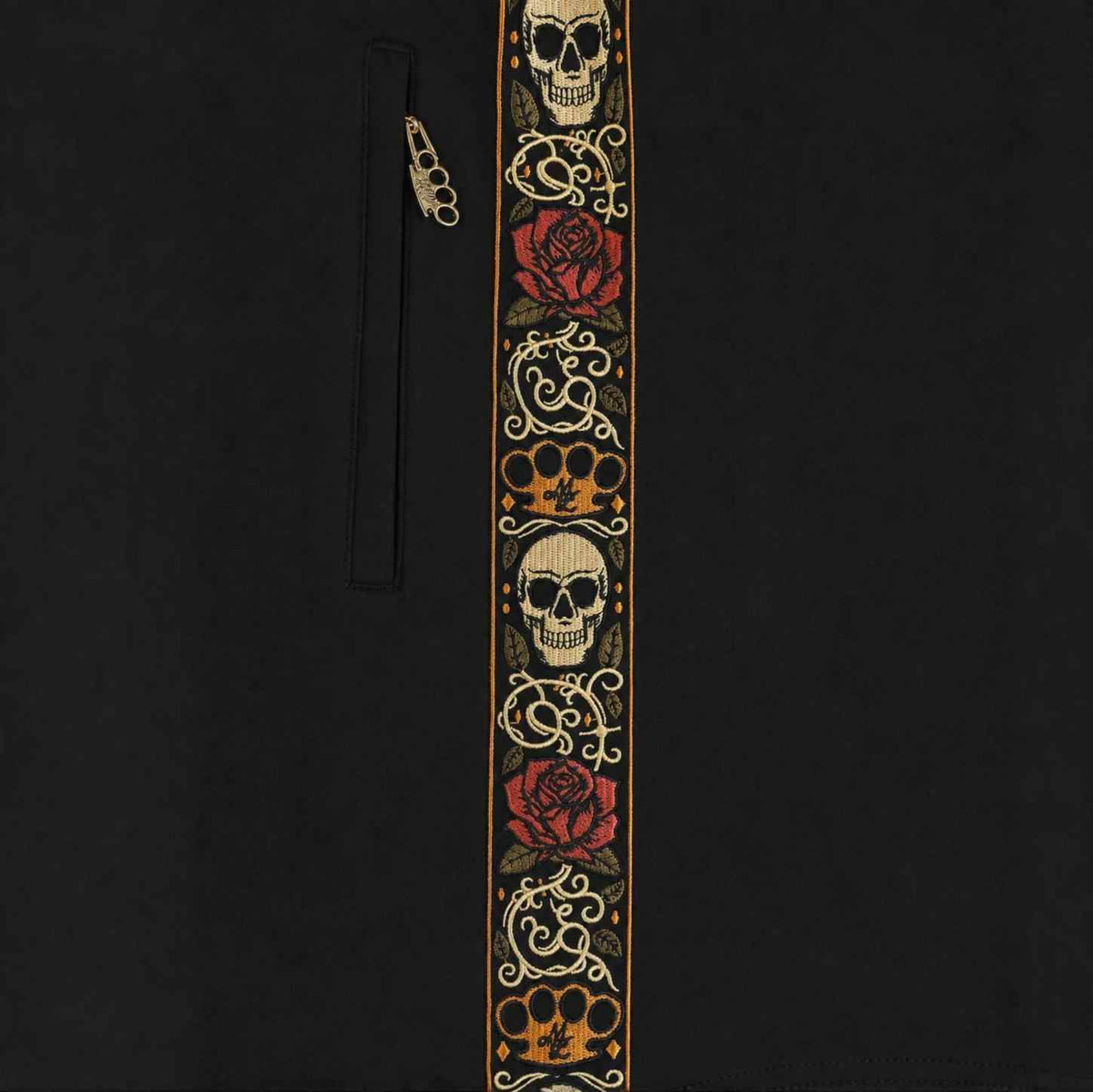 Gros plan de la bande brodée Calavera avec têtes de mort, roses et logo MVL près de la poche zippée