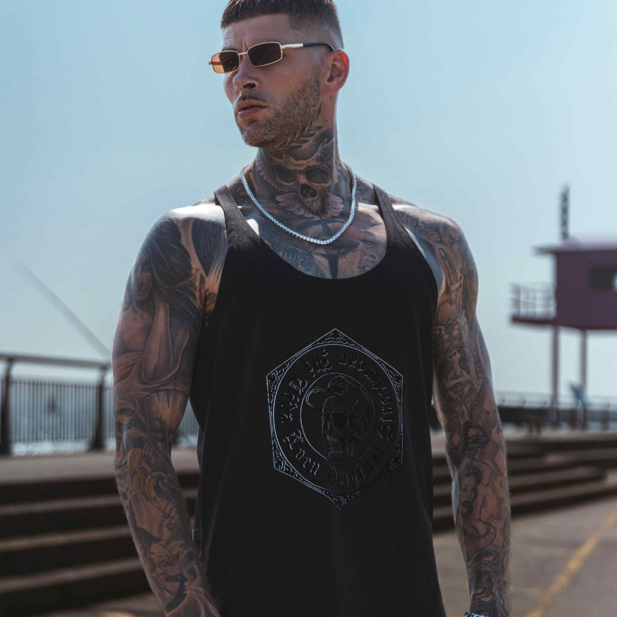 Canotta MVL Original streetwear nera indossata da modello su una banchina, fotografata dal basso