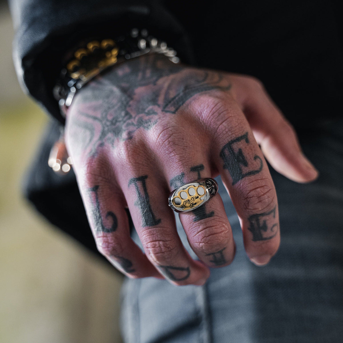 MVL Logo ring zilver aan de vinger van een getatoeëerde hand, close-up