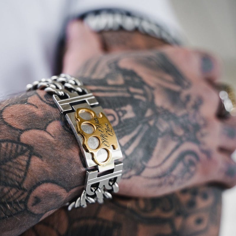 Zilveren MVL armband met gouden MVL logo om de getatoeëerde pols, close-up