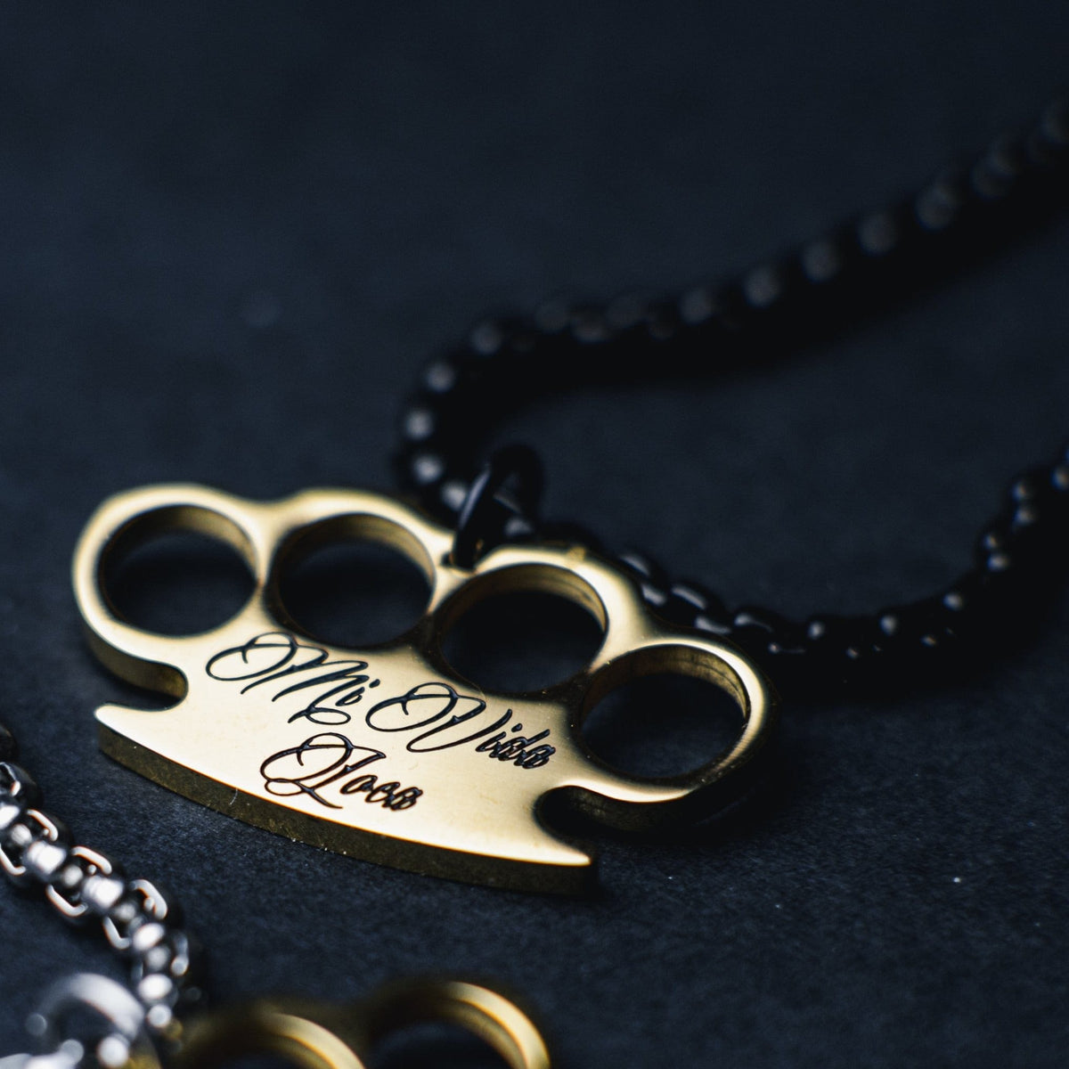 Gros plan du pendentif logo MVL doré gravé Mi Vida Loca sur la chaîne noire