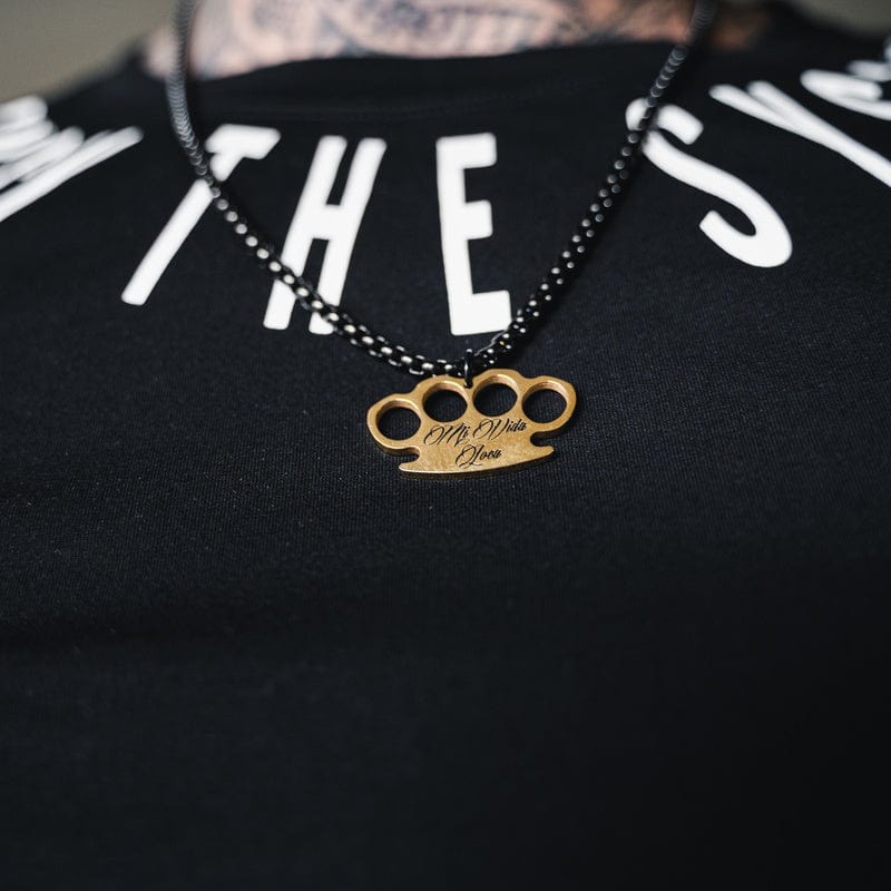 Logo chain MVL noire avec pendentif logo MVL doré, portée sur un T-shirt noir