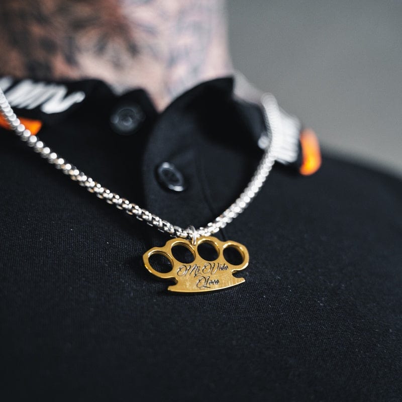 Chaîne MVL Logo argent/or portée sur un haut noir, gros plan du pendentif