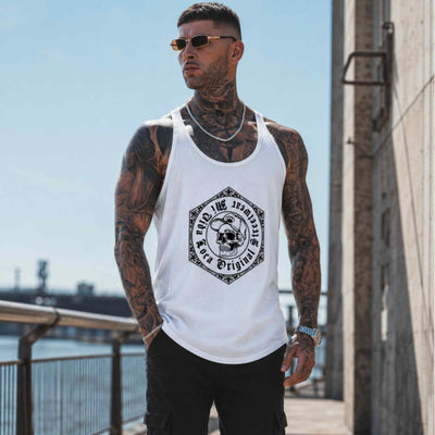 Modelo con tatuajes y gafas de sol lleva la camiseta de tirantes MVL Original streetwear blanca junto al agua